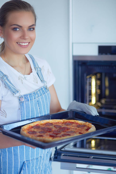 Happy young woman cooking pizza at home - 写真・画像