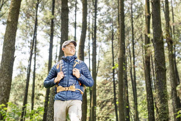 Handsome asian traveler with backpack on the forest - Fotó, kép