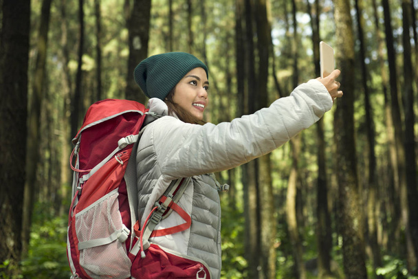 Hermosa asiática turista tomando selfie con su teléfono en el bosque
 - Foto, imagen