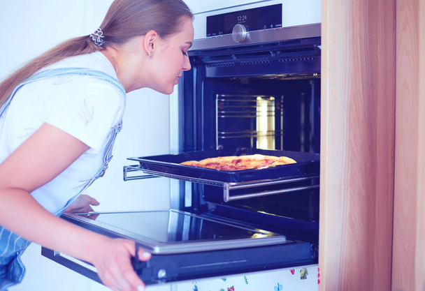 Happy young woman cooking pizza at home - Zdjęcie, obraz