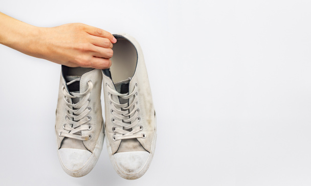 Bílé špinavé tenisky boty s rukou na bílém pozadí - Fotografie, Obrázek