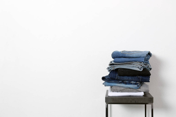 Stack of different jeans on table against white background. Space for text - Fotó, kép