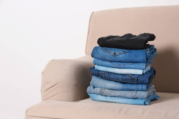 Stack of different jeans on sofa against white background - Photo, image