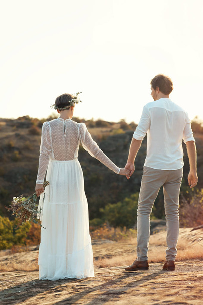 Happy newlyweds with beautiful field bouquet outdoors - Zdjęcie, obraz