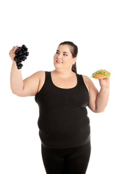 Overweight woman with hamburger and grapes on white background - Fotoğraf, Görsel