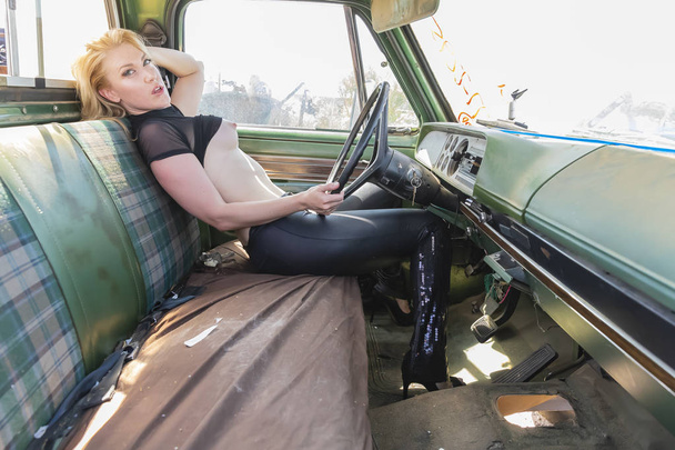 A beautiful implied blonde model posing in a auto salvage yard. - Photo, image