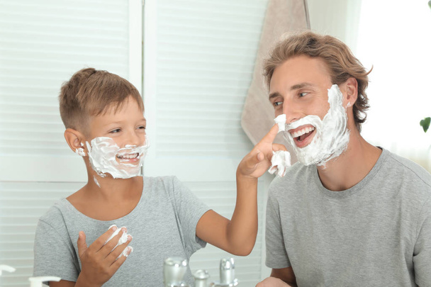 Father and son shaving together on color background - Fotografie, Obrázek