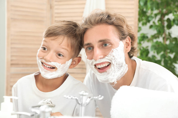 Father and son shaving together on color background - Fotó, kép