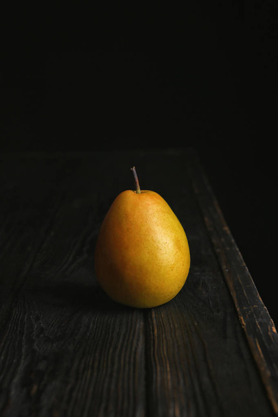 Ripe pear on wooden table against dark background - Foto, Bild