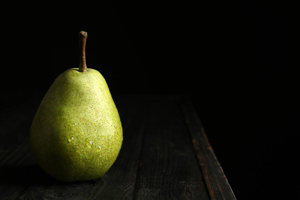 Ripe pear on wooden table against dark background. Space for text - Foto, Bild