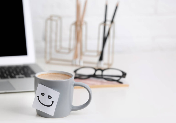 Coffee cup with cute sticker on table at modern workplace - Photo, Image