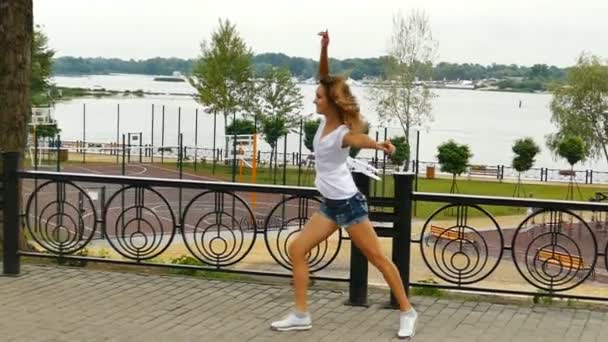 Young  smiling girl does dancing figures on city street. slow motion - Footage, Video