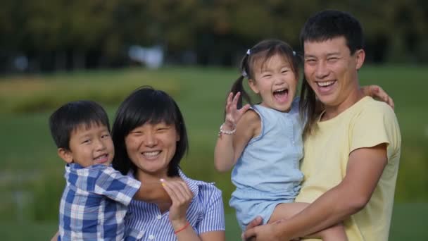 Aufgeregte vierköpfige asiatische Familie lacht im Park - Filmmaterial, Video
