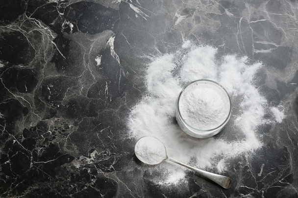 Jar and spoon with baking soda on grey background, top view. Space for text - Foto, Imagen