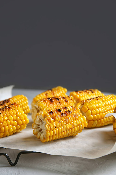 Cooling rack with grilled corn cobs on table against gray background. Space for text - Fotó, kép