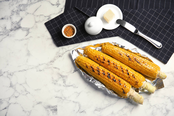 Fresh grilled tasty corn cobs served with butter on marble table, top view. Space for text - Photo, Image
