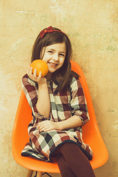 Happy girl with cute smile and orange in hand smiling - Fotoğraf, Görsel