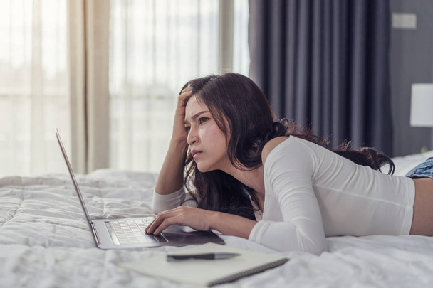 стресова жінка використовує ноутбук на ліжку
 - Фото, зображення