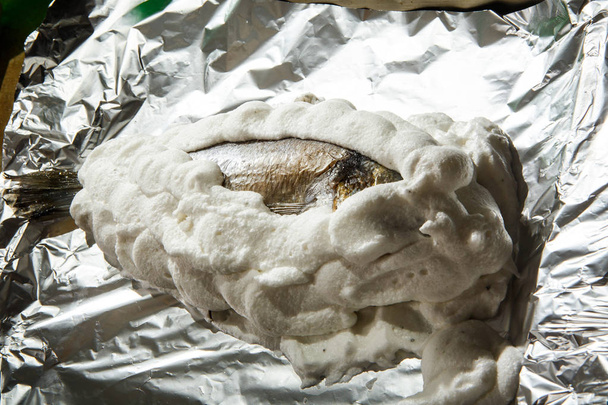 Dorado borított felvert tojásfehérjét a sóval, a fólia - Fotó, kép