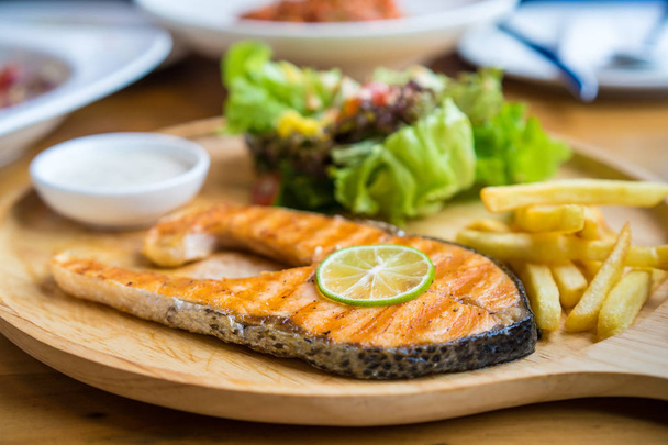 Стейк з лосося на грилі з перцем та лимоном на дерев'яній тарілці
 - Фото, зображення