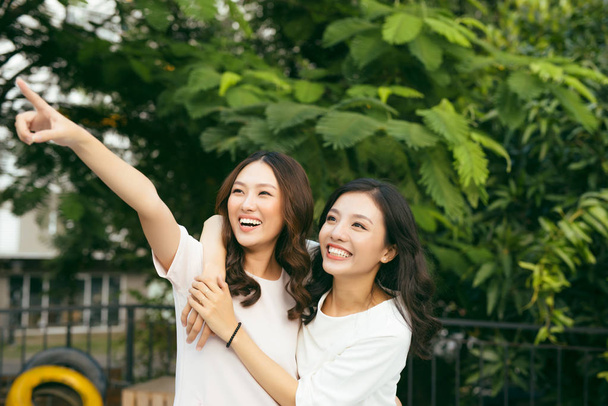 Две молодые красивые девушки смеются, гуляя в зеленом саду
 - Фото, изображение