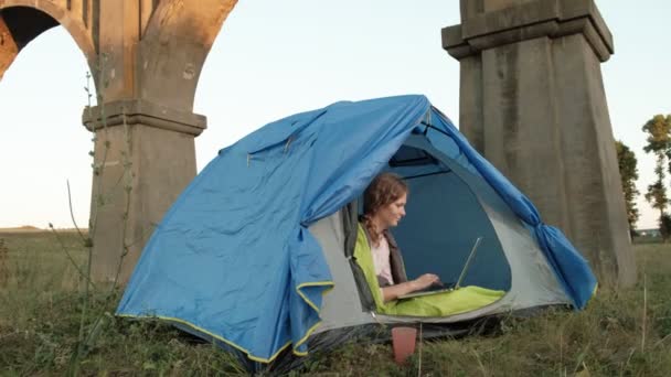Young woman working behind a laptop in a tourist tent near the old bridge - Footage, Video