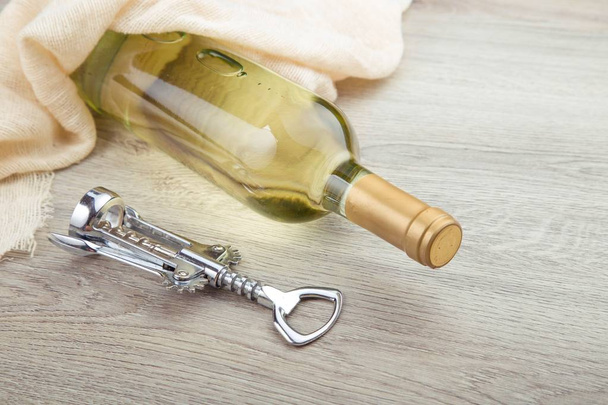 Wine bottle with corkscrew on wooden background - Φωτογραφία, εικόνα
