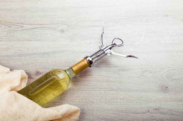 Wine bottle with corkscrew on wooden background - Foto, imagen