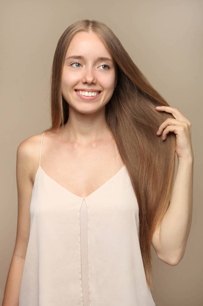 Girl with long blond hair on beige background. Concept hair care. - Фото, изображение
