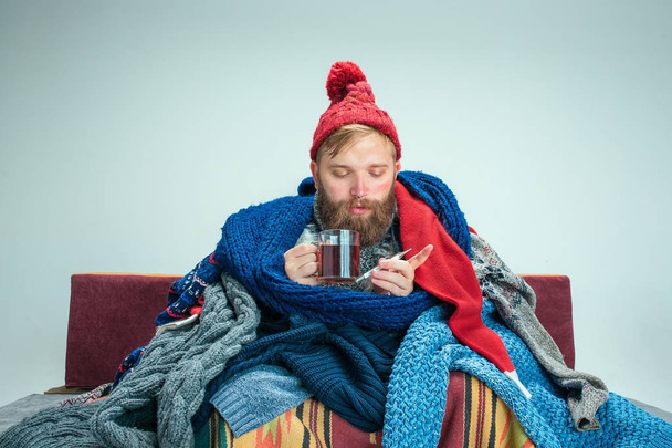 Bearded Man with Flue Sitting on Sofa at Home. Healthcare Concepts. - Фото, изображение