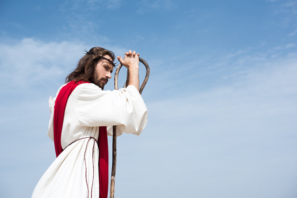 elbise, kırmızı kuşak ve mavi gökyüzü karşı ahşap kadrosunda eğilerek dikenli taç İsa'nın yan görünüm - Fotoğraf, Görsel