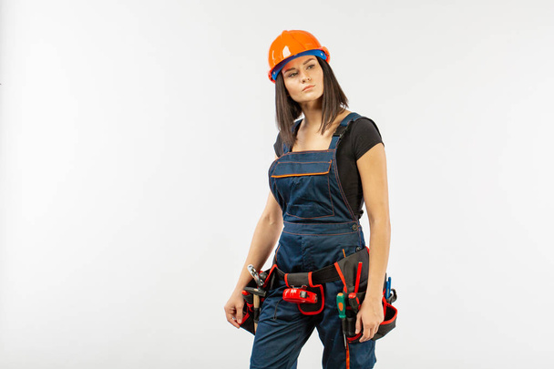 Pretty builder girl with helmet and belt of tools over white background - Foto, Imagem