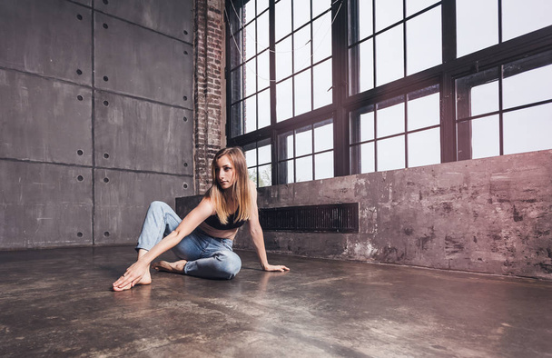 young beautiful woman dancer contemporary in tops and jeans sits on the floor in dance studio - Foto, immagini