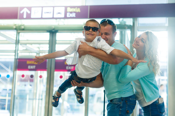 Nuori perhe pojan kanssa hauskaa lentokentällä ennen lähtöä
  - Valokuva, kuva