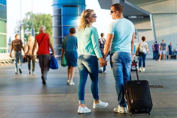 出発前に空港で荷物を持って歩く若いカップル  - 写真・画像