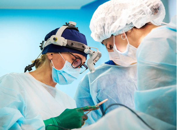 Chirurgia, medicina e concetto di persone - chirurghi in sala operatoria in ospedale durante il loro lavoro.Il chirurgo con una lente d'ingrandimento durante un intervento chirurgico in sala operatoria
 - Foto, immagini