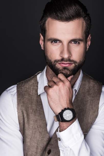 portrait of thoughtful elegant bearded man with wristwatch, isolated on grey - 写真・画像