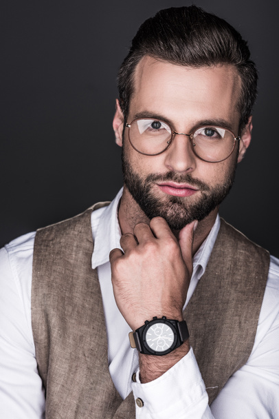 portrait of thoughtful bearded man posing in trendy eyeglasses, isolated on grey - Foto, afbeelding