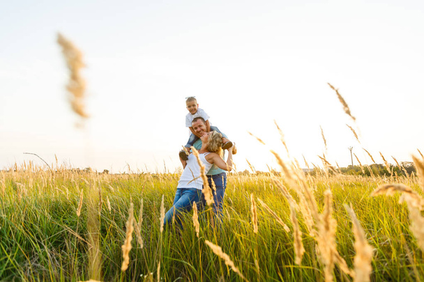 Yürüyüş ve yeşil alana günbatımında eğleniyor oğlu ile genç Aile - Fotoğraf, Görsel