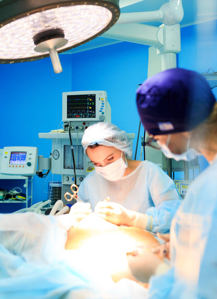Chirurgie, Medizin und Personalkonzept - drei Chirurgen während ihrer Arbeit im Operationssaal des Krankenhauses. - Foto, Bild