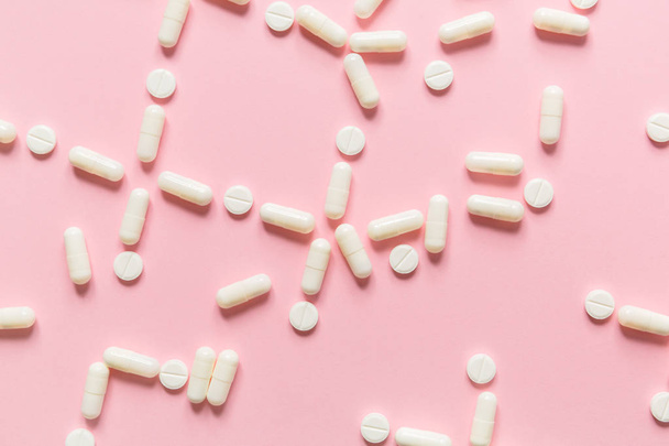 Vaaleanpunainen tausta valkoiset tabletit ja pillerit
. - Valokuva, kuva