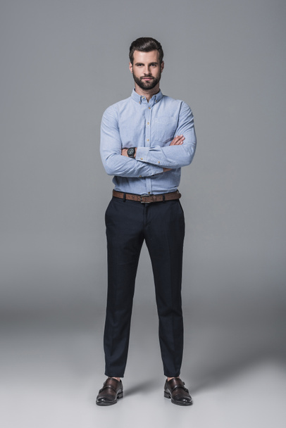 confident stylish business man posing with crossed arms, on grey - Fotografie, Obrázek