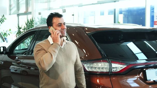 Az üzletember, beszél a telefonon, miközben ő az autót szalon - Fotó, kép