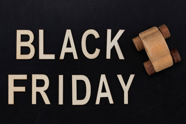 black Friday - text in wooden letters on blackBoard  with wooden car. Copy space. - Photo, Image