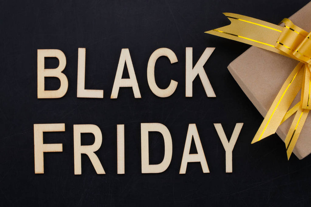 black Friday - text in wooden letters on blackBoard  with gift . Copy space. - Fotoğraf, Görsel
