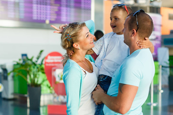Пусть начнётся путешествие. Портрет милой пары, держащей своего маленького сына в зале аэропорта
 - Фото, изображение