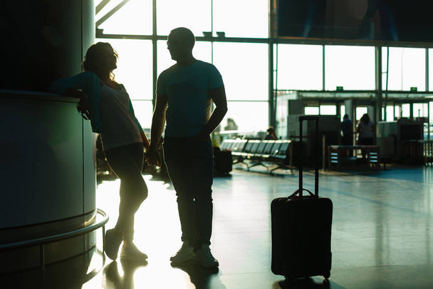 Νεαρό ζευγάρι αναμονή για αναχώρηση στον τερματικό σταθμό του αεροδρομίου - Φωτογραφία, εικόνα