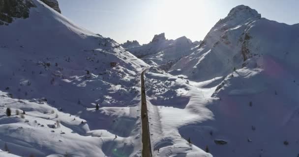 Προς τα εμπρός εναέρια παρακάτω αυτοκίνητα στο δρόμο σε χιονισμένο κοιλάδα στο πέρασμα του Valparola. Ηλιόλουστο ηλιοβασίλεμα ή Ανατολή του ηλίου, με καθαρό ουρανό. Χειμώνα πτήση drone establisher.4k εξωτερική φύση βουνά Δολομίτες ιταλικές Άλπεις - Πλάνα, βίντεο