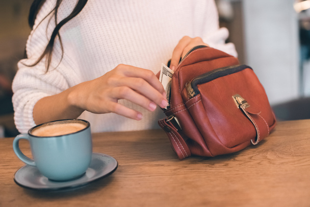 カフェでコーヒー カップとテーブルでバッグから現金を引き出す女性の部分的なビュー  - 写真・画像