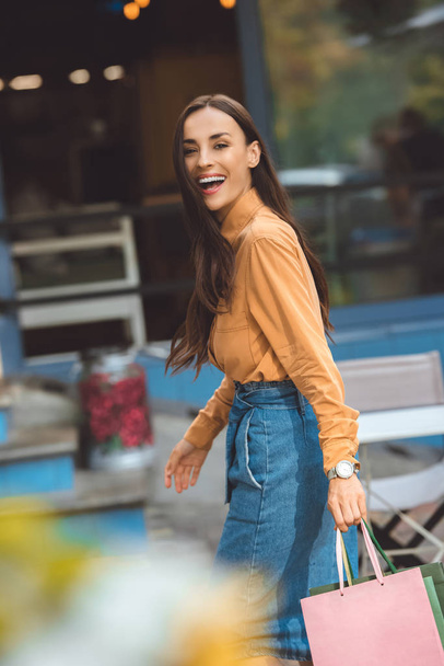 laughing stylish young woman walking with shopping bags at city street - Valokuva, kuva